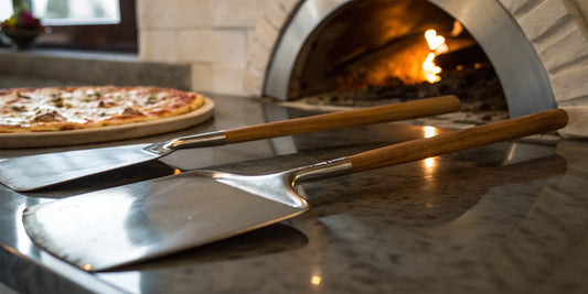A metal pizza peel resting on a counter beside a hot, freshly baked pizza.